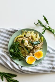 Home A top view of a healthy vegetable rice dish with soft-boiled eggs on a light green plate.